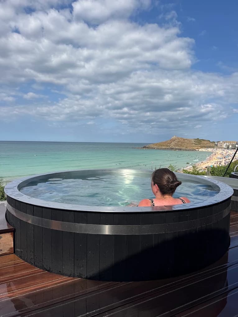 View from inside a bespoke round cold plunge at Kiln Sauna, looking over Porthmeor Beach